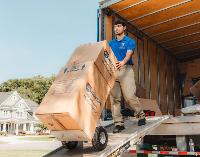 495 Movers crew rolling dolly with boxes down truck ramp